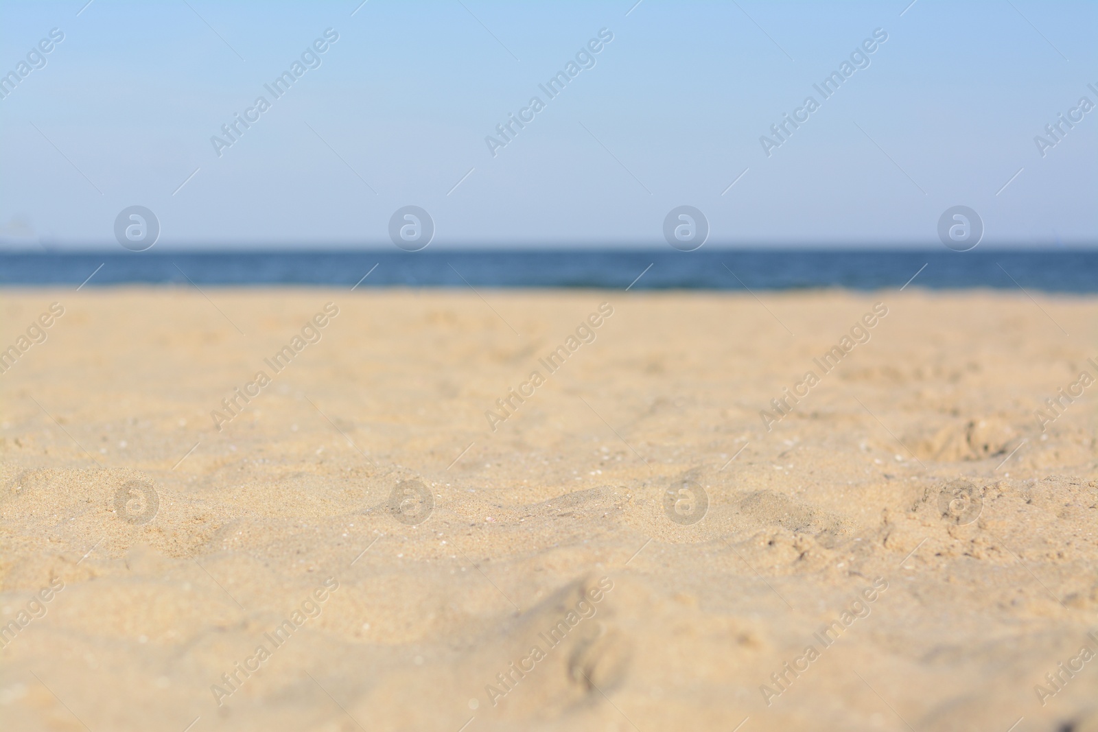 Photo of Blurred view of sandy beach near sea on sunny day