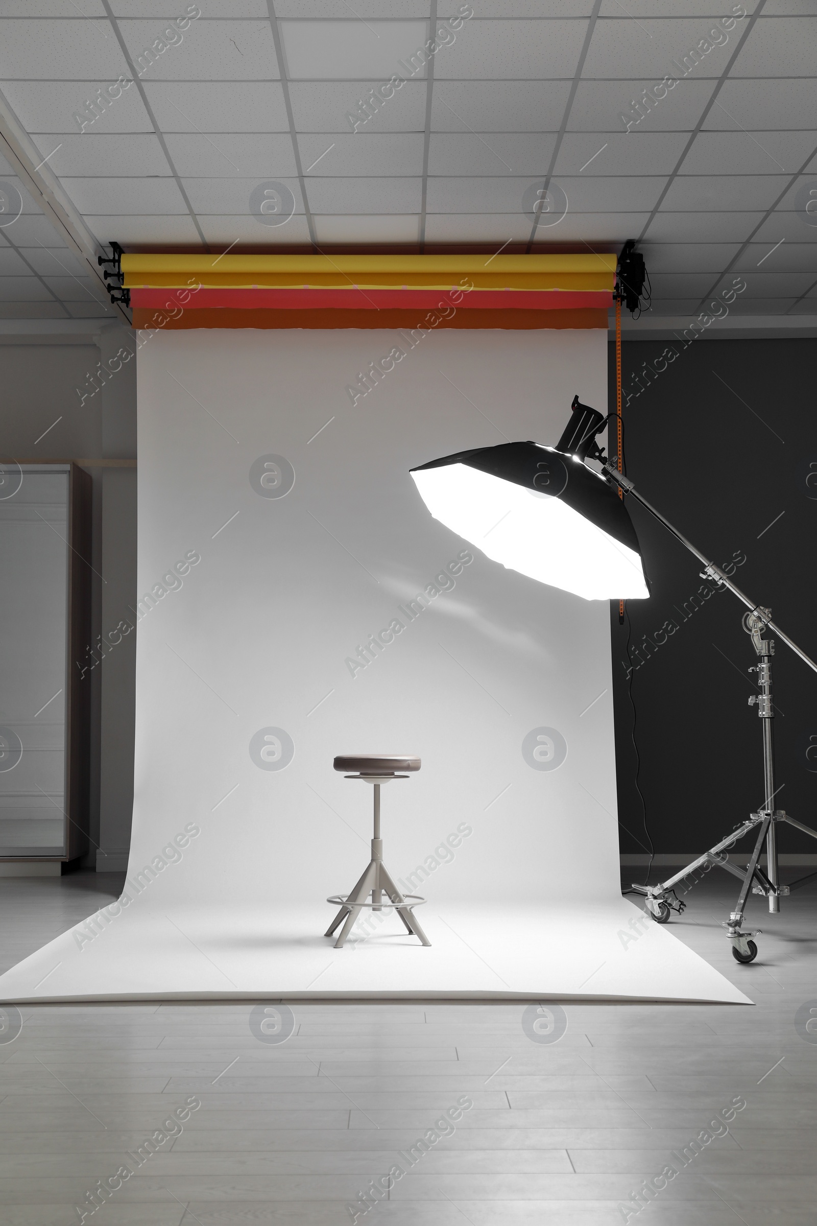 Photo of White photo background, stool and professional lighting equipment in modern studio