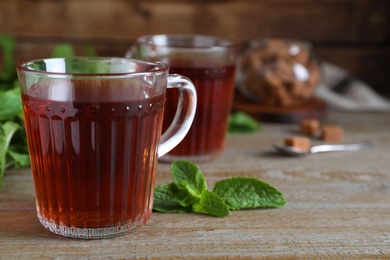 Photo of Cup with hot aromatic mint tea on wooden table, closeup. Space for text