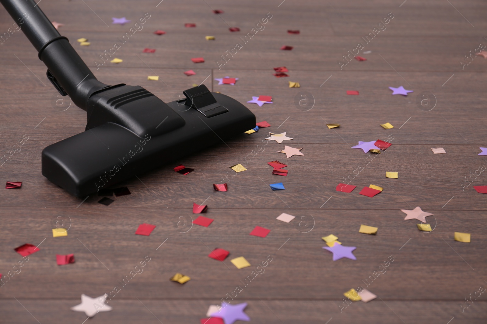 Photo of Vacuuming confetti from wooden floor in room