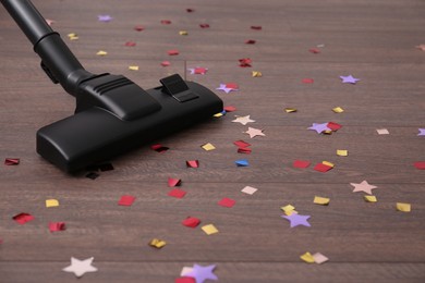 Photo of Vacuuming confetti from wooden floor in room