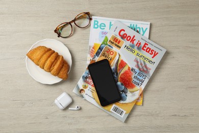 Photo of Flat lay composition with different magazines and smartphone on light wooden table