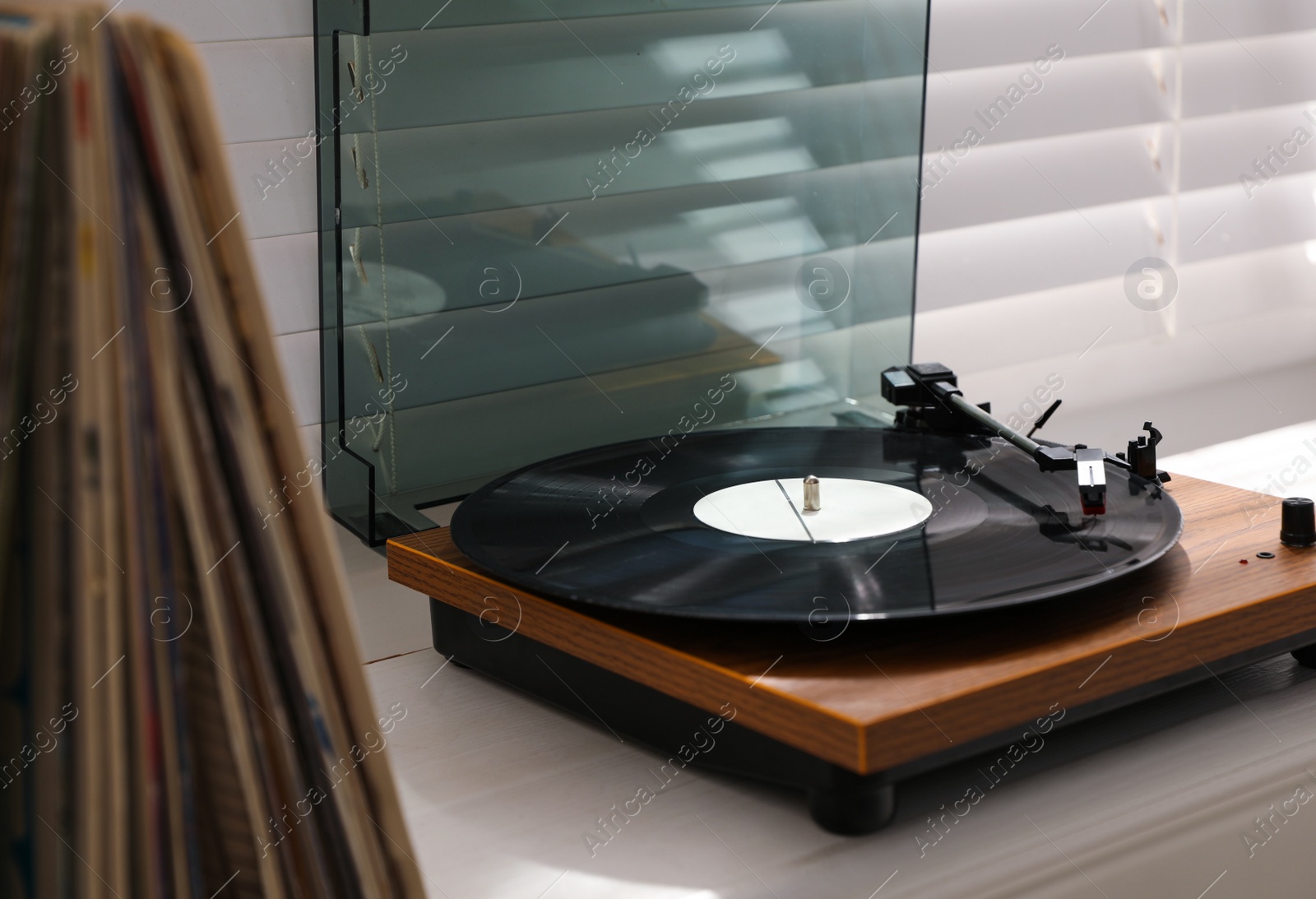Photo of Stylish turntable with vinyl disc on windowsill in room