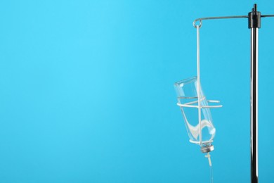 Photo of IV infusion set on light blue background. Space for text