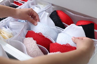 Photo of Woman putting underwear into organizer in drawer, closeup