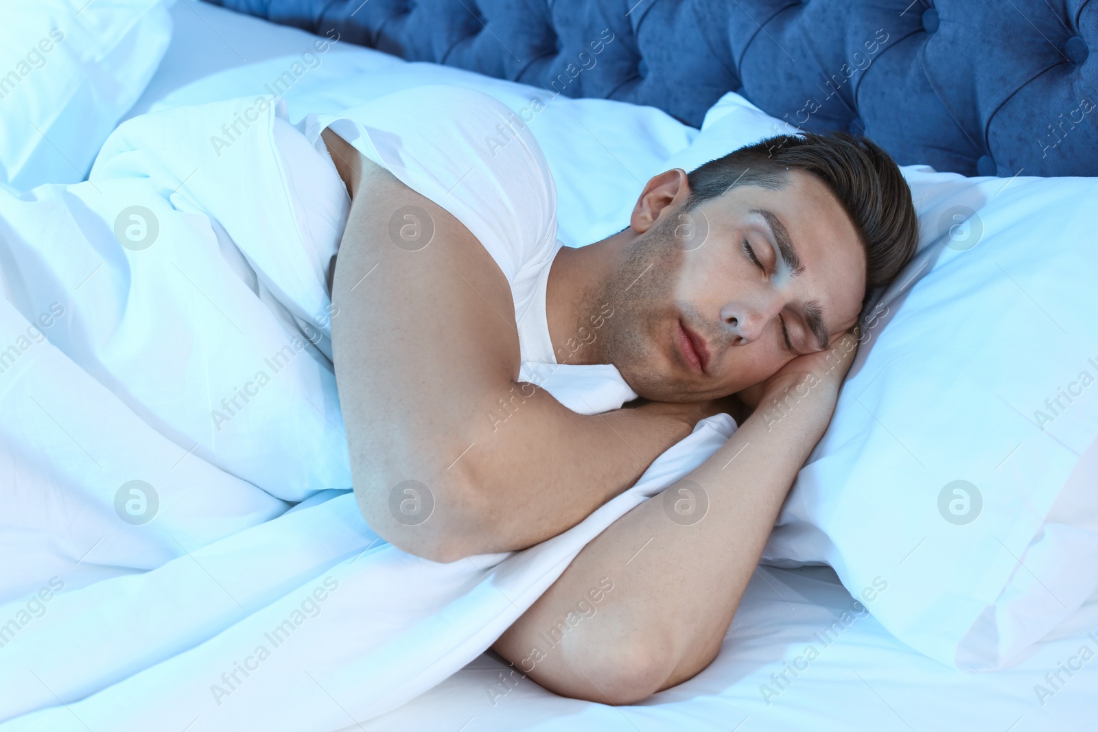 Photo of Young man sleeping in bed at night