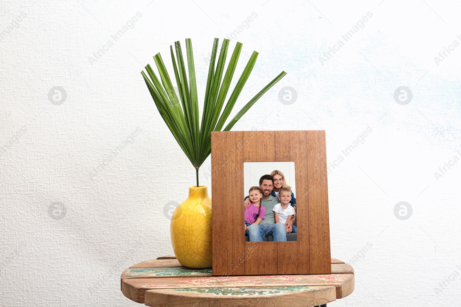 Image of Portrait of family in photo frame on table near white wall