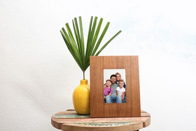 Portrait of family in photo frame on table near white wall