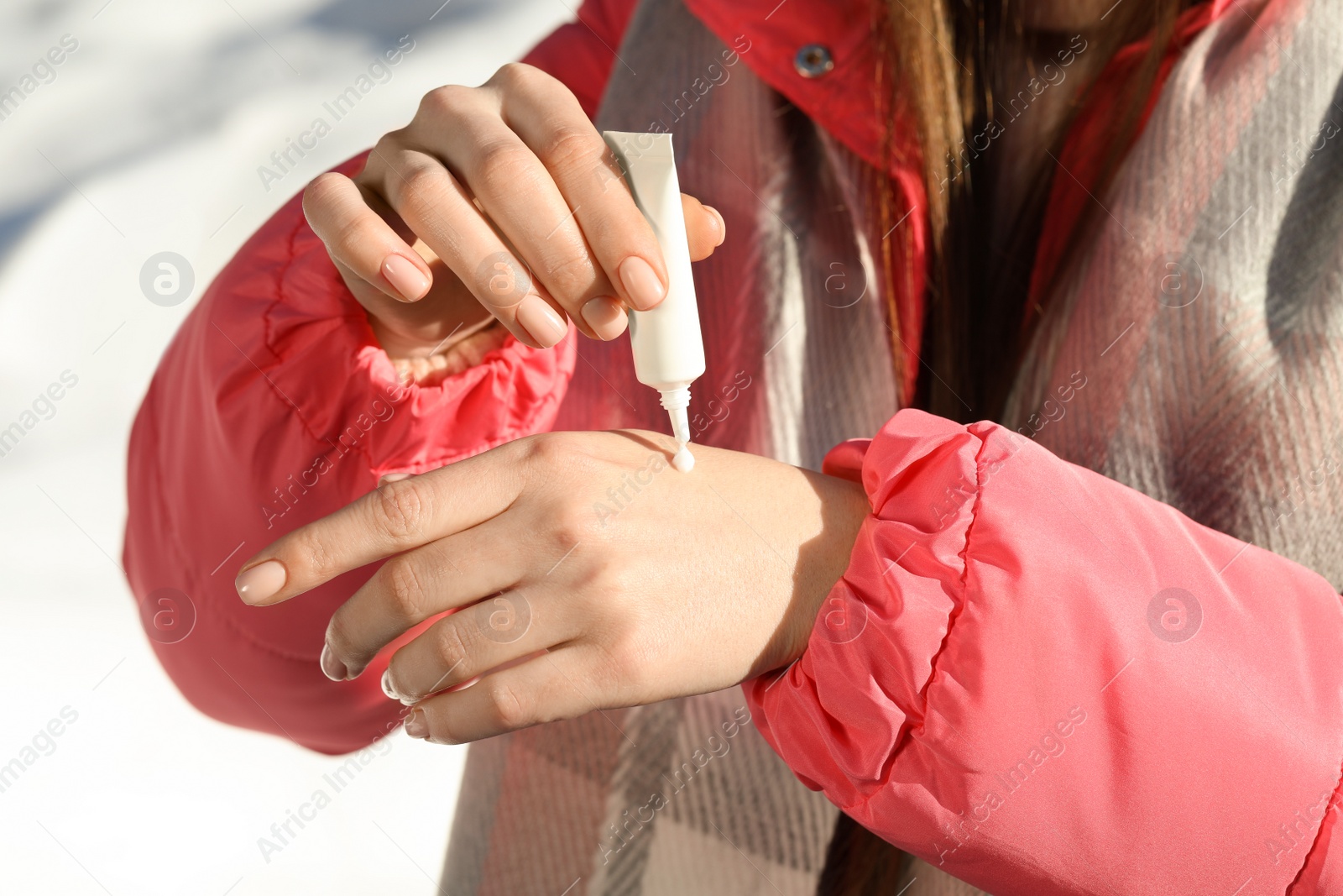 Photo of Woman applying moisturizing cream on hands in winter, closeup