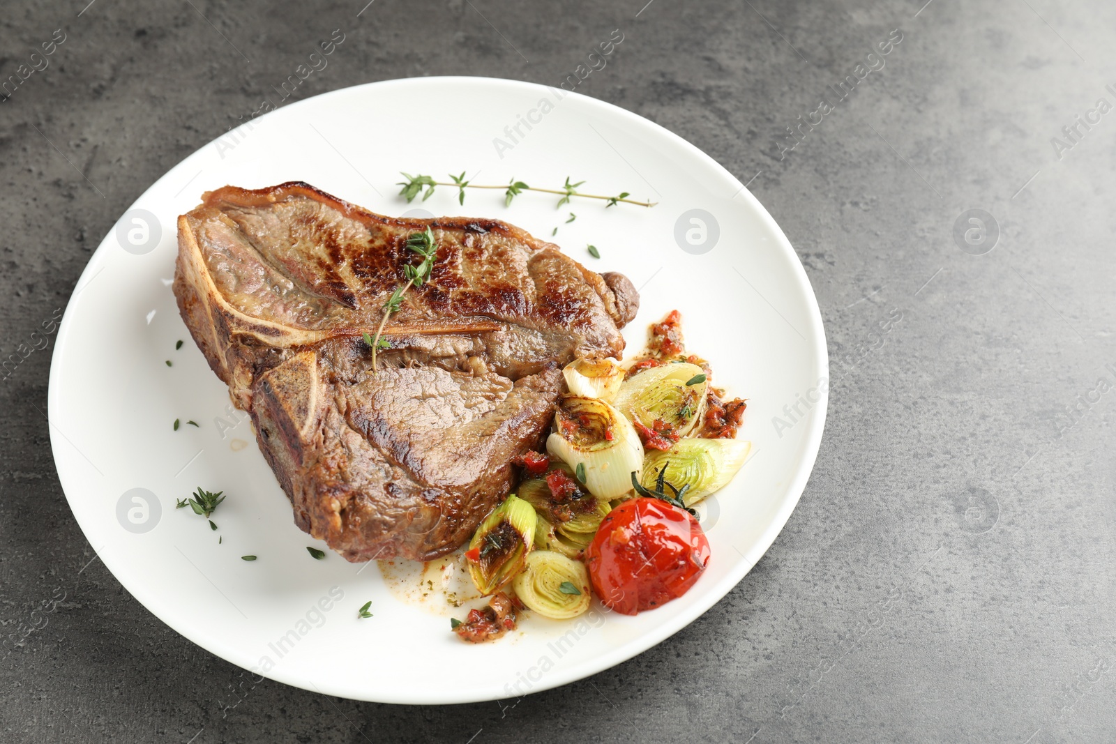 Photo of Delicious fried beef meat and vegetables on grey table