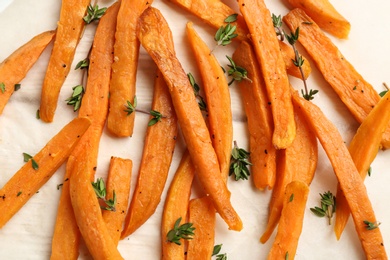 Photo of Tasty sweet potato fries on parchment, closeup