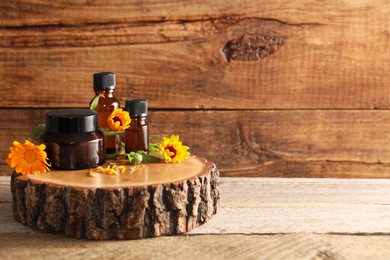 Different cosmetic products and beautiful calendula flowers on wooden table, space for text