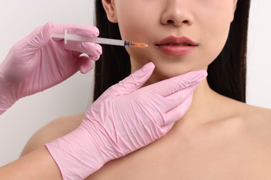 Photo of Woman getting lip injection on white background, closeup