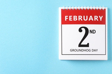 Top view of calendar with date February 2nd on light blue background, space for text. Groundhog day