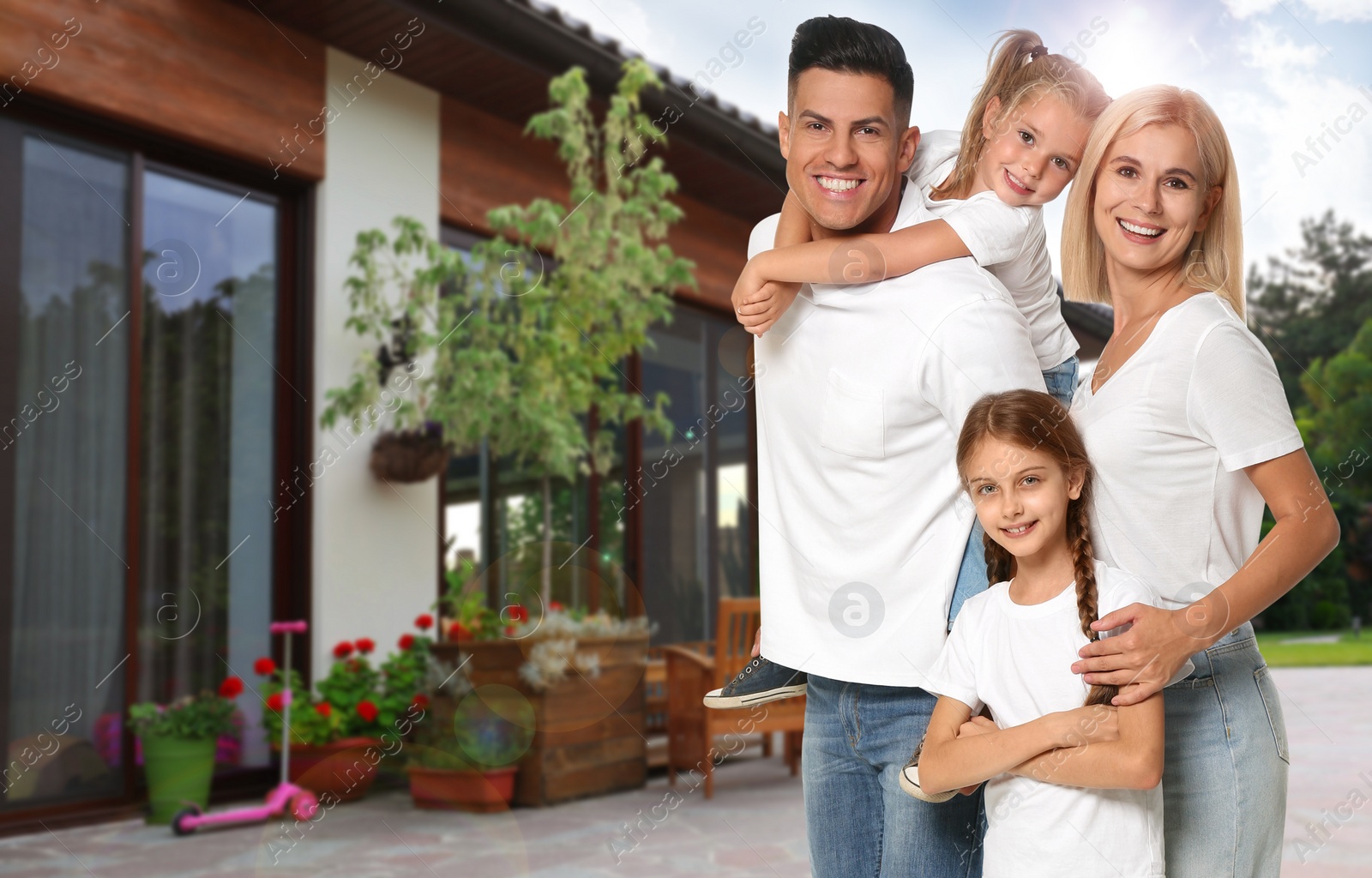 Image of Happy family standing in front of their house on sunny day 