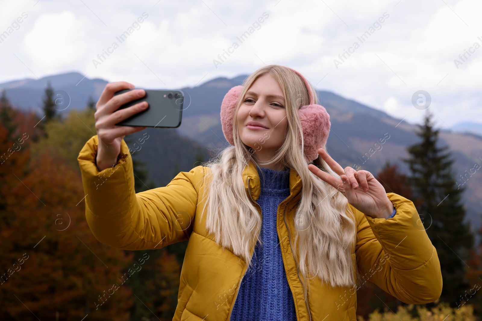 Photo of Young woman taking selfie in mountains on autumn day