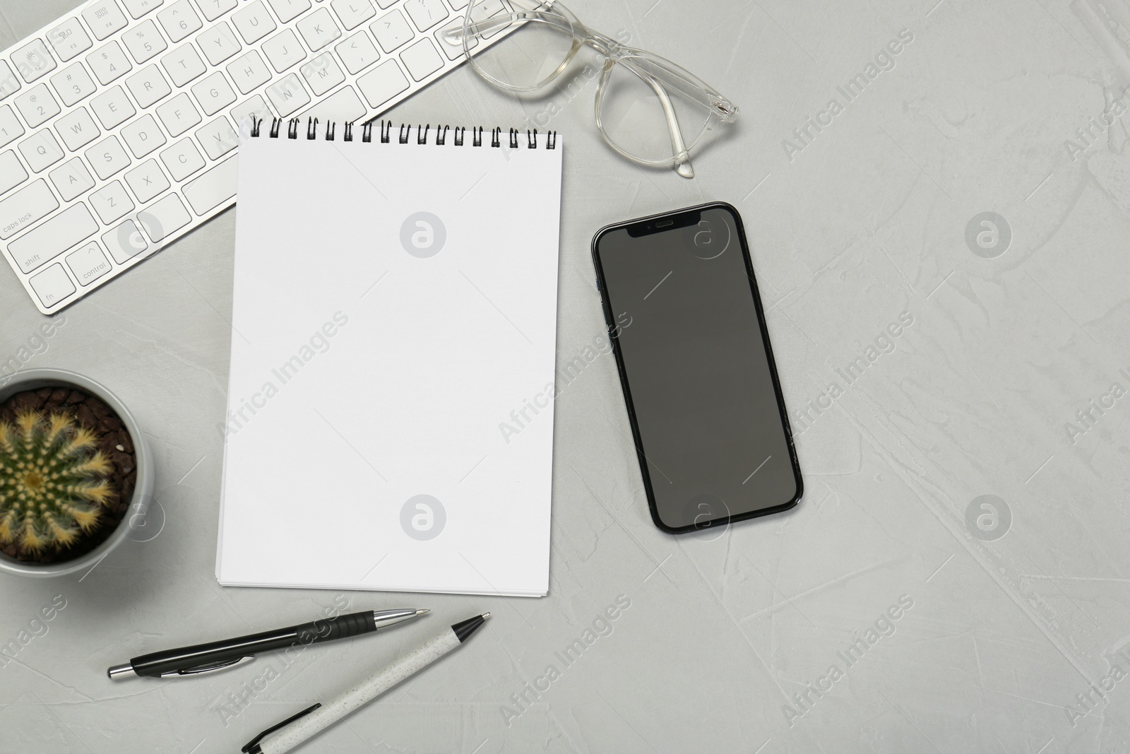 Photo of Flat lay composition with open notebook and smartphone on light grey table