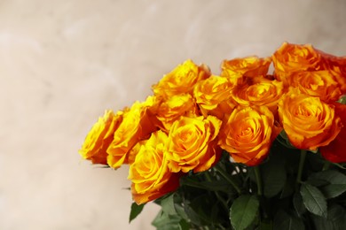 Beautiful bouquet of orange roses on beige background, closeup