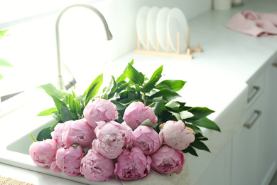 Bouquet of beautiful pink peonies in kitchen sink