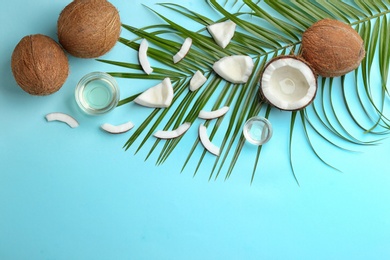 Flat lay composition with ripe coconuts, natural organic oil and space for text on blue background