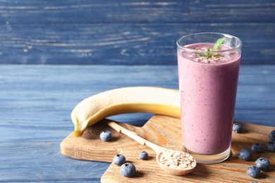 Glass of blueberry smoothie with oatmeal on wooden table