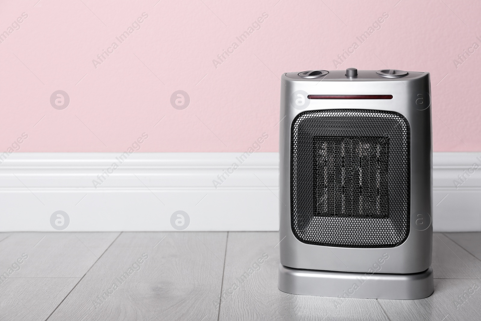 Photo of Modern electric fan heater on floor in room, space for text