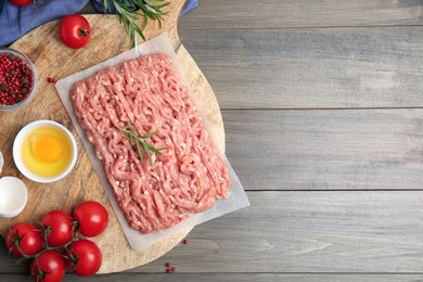 Photo of Raw chicken minced meat and ingredients on grey wooden table, flat lay. Space for text