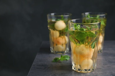 Photo of Glasses with tasty melon ball drink on table against dark background. Space for text