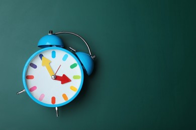 Photo of Alarm clock on green chalkboard, top view with space for text. School time