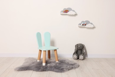 Photo of Beautiful children's room with light wall, chair and toys. Interior design