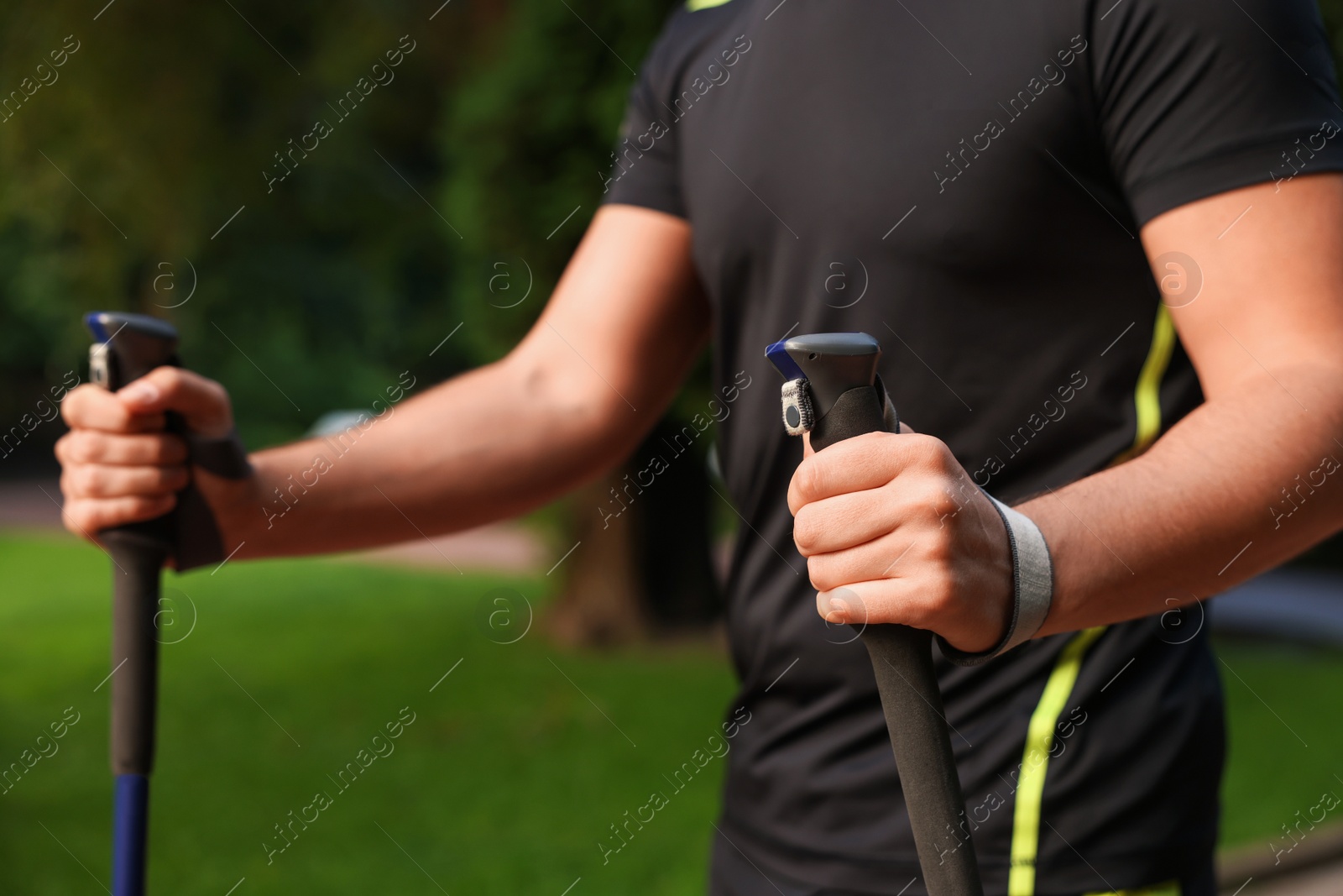 Photo of Man practicing Nordic walking with poles outdoors, closeup