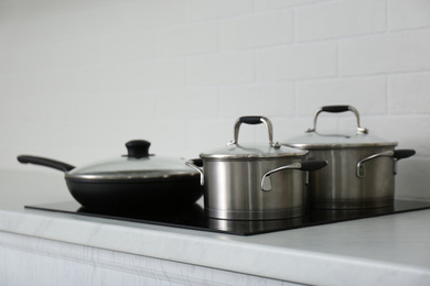 Saucepots and frying pan on induction stove in kitchen