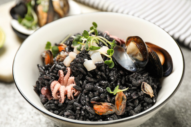Photo of Delicious black risotto with seafood in bowl on table