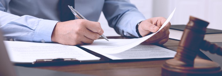 Lawyer working with document at wooden table in office, closeup. Banner design