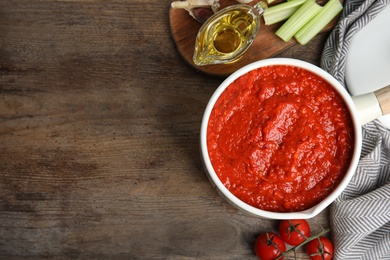 Photo of Flat lay composition with pan of tomato sauce on wooden table. Space for text
