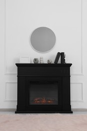 Black stylish fireplace with accessories under round mirror in cosy living room