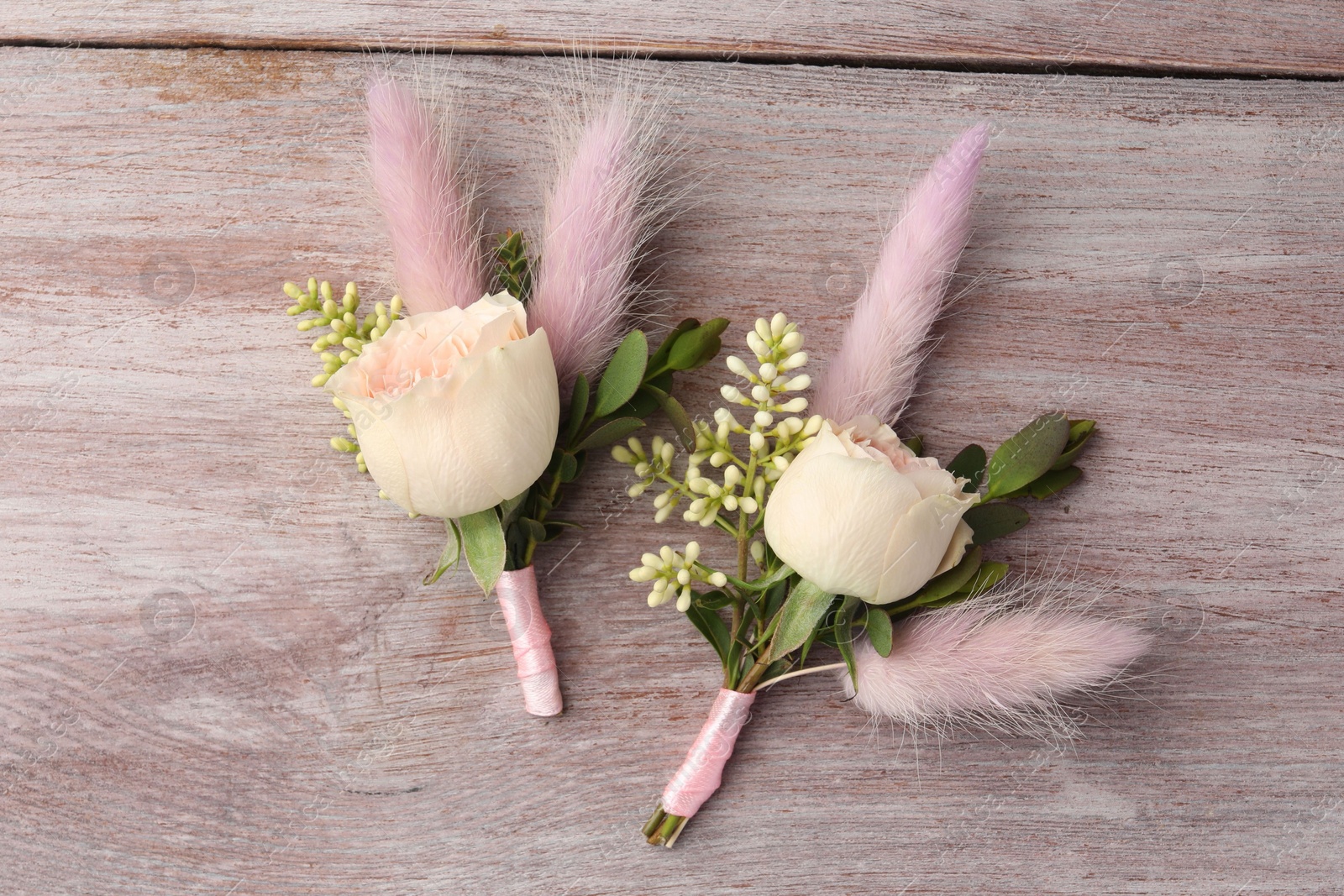 Photo of Small stylish boutonnieres on light wooden table, top view