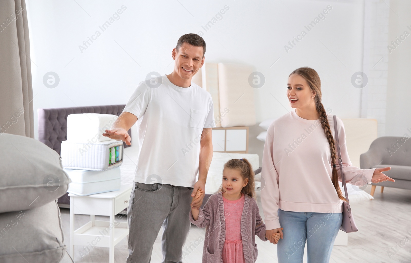 Photo of Happy family choosing cushion in mattress store