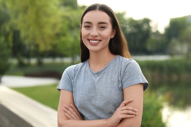 Portrait of beautiful woman with crossed arms outdoors. Attractive lady smiling and looking into camera