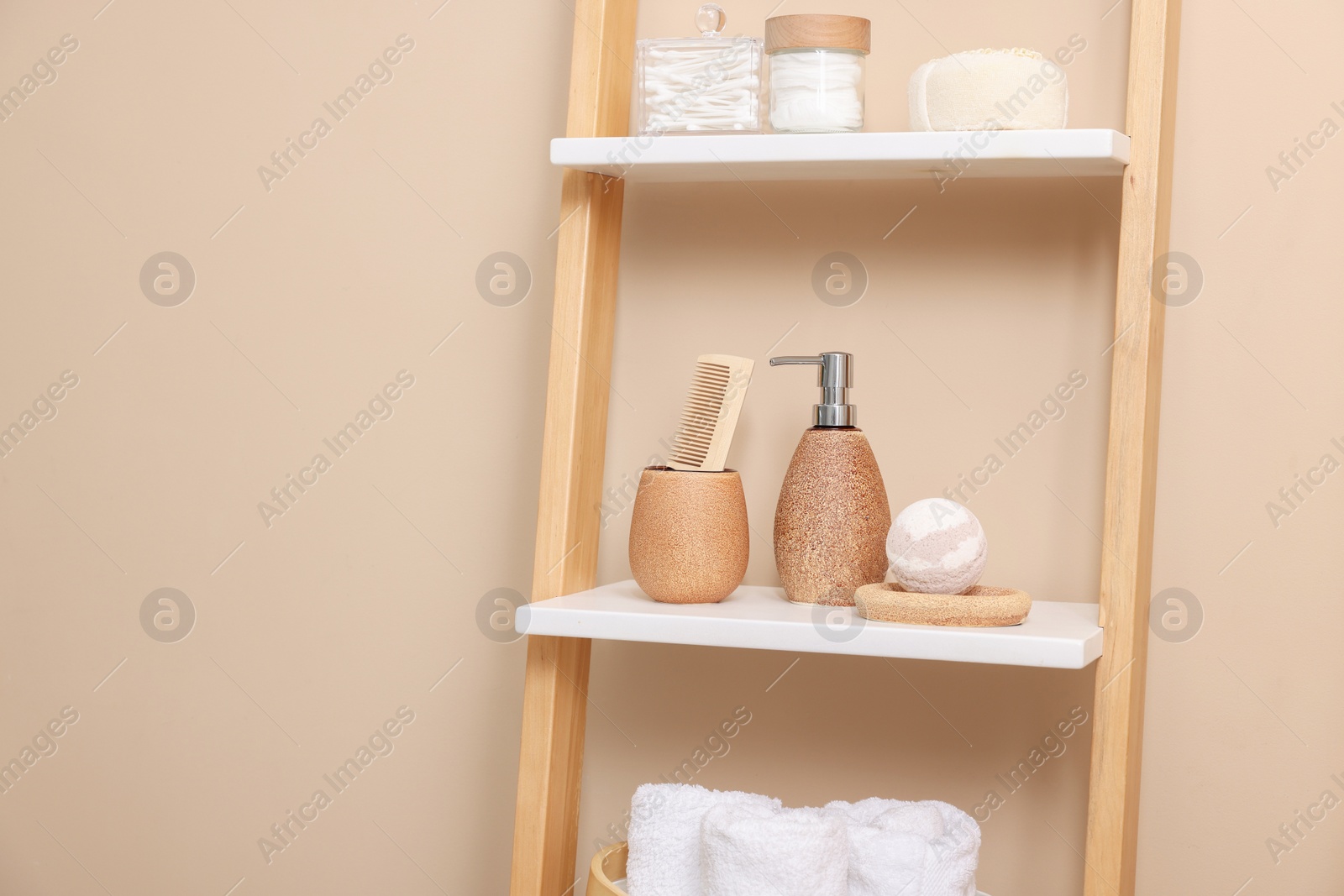 Photo of Different bath accessories and personal care products on shelving unit near beige wall, space for text