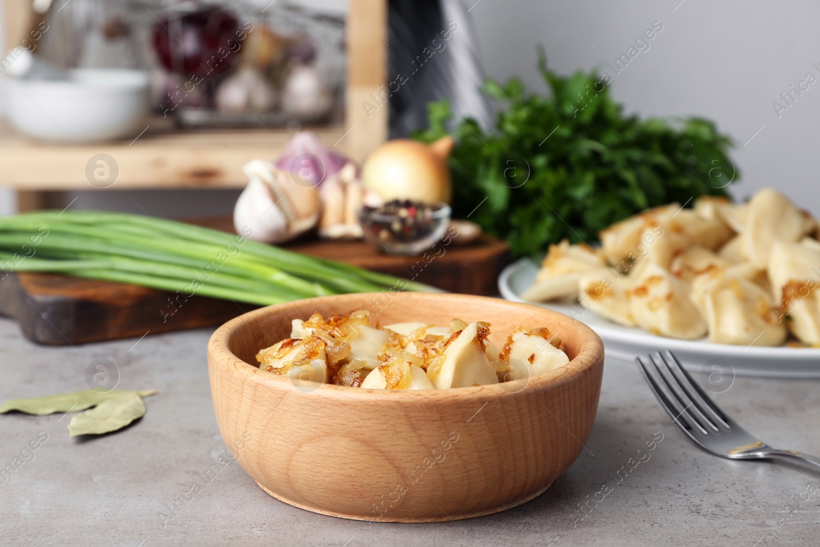 Photo of Delicious cooked dumplings with fried onion on grey table