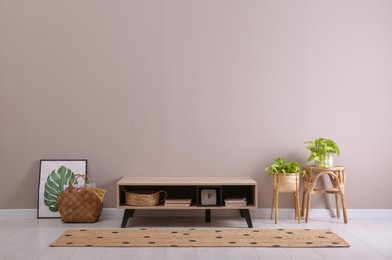 Photo of Elegant room interior with wooden cabinet and beautiful houseplants near beige wall. Space for text