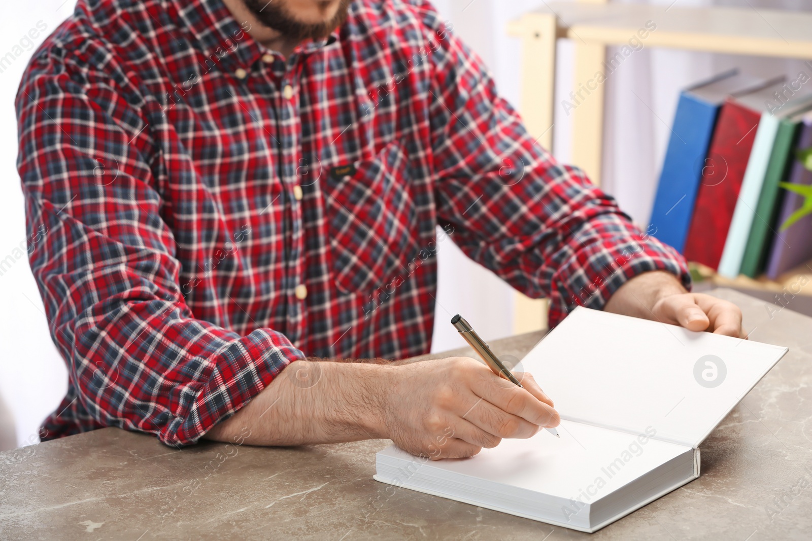 Photo of Writer signing autograph in book at table, closeup