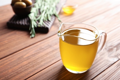 Photo of Jug with fresh rosemary oil on table