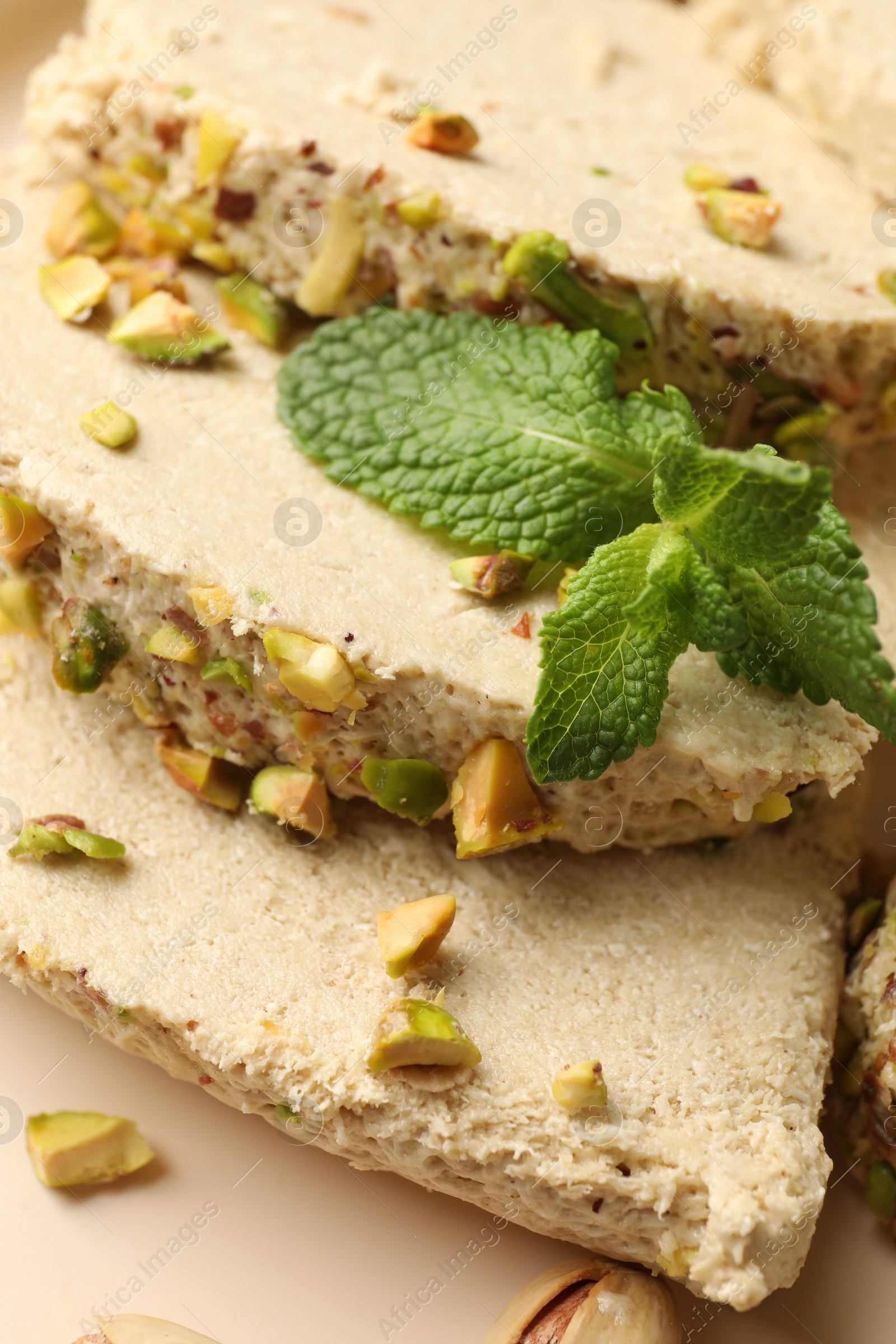 Photo of Pieces of tasty halva with pistachios and mint on table, above view