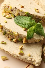 Photo of Pieces of tasty halva with pistachios and mint on table, above view