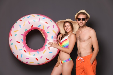 Photo of Young couple in beachwear with inflatable ring on dark background