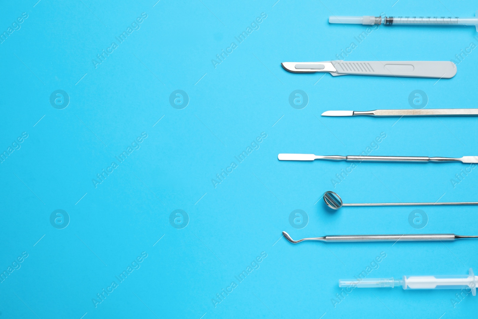 Photo of Set of different dentist's tools and syringe on light blue background, flat lay. Space for text