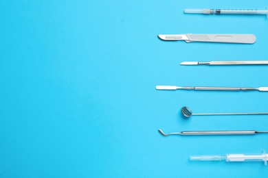 Photo of Set of different dentist's tools and syringe on light blue background, flat lay. Space for text