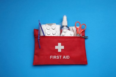 Photo of First aid kit on light blue background, top view